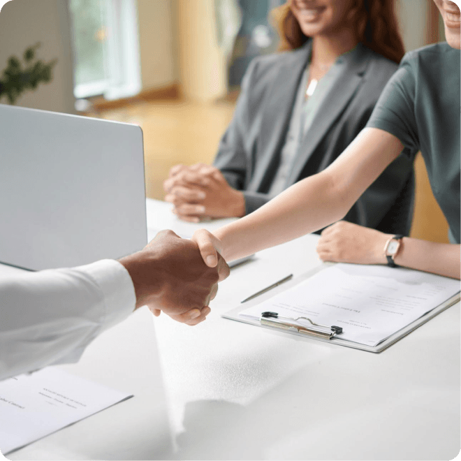 Professionals shaking hands over a desk after a successful hire